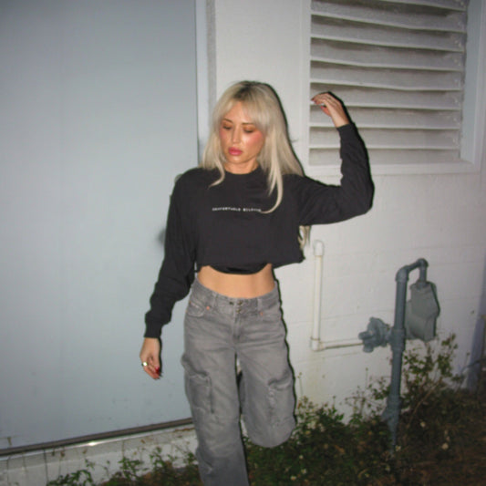 Woman wearing Comfortable Silence black cropped long sleeve tee in a streetwear lifestyle photo