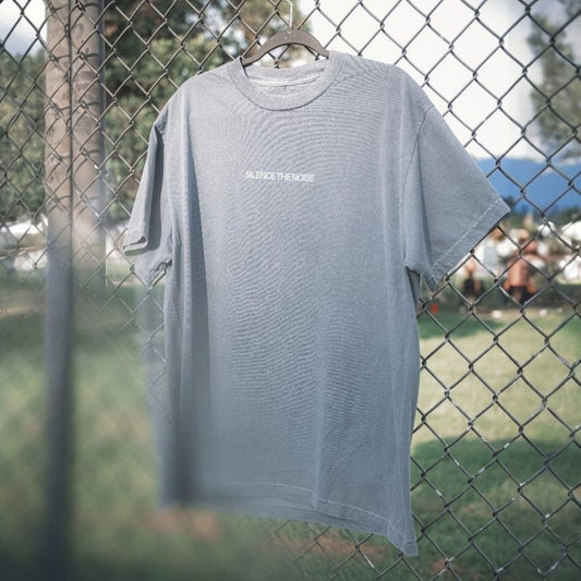 Faded indigo t-shirt hanging on a chain link fence