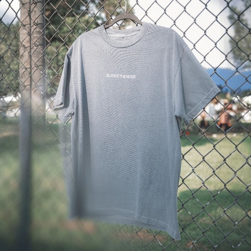 Faded indigo t-shirt hanging on a chain link fence
