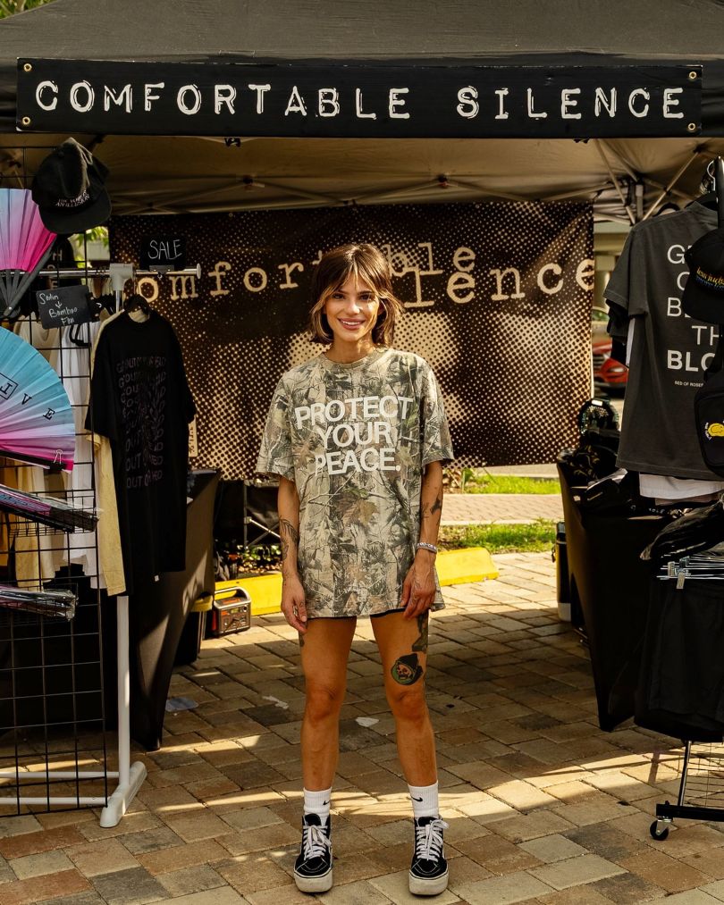 Missy standing in front of a 'Comfortable Silence' booth with merchandise.
