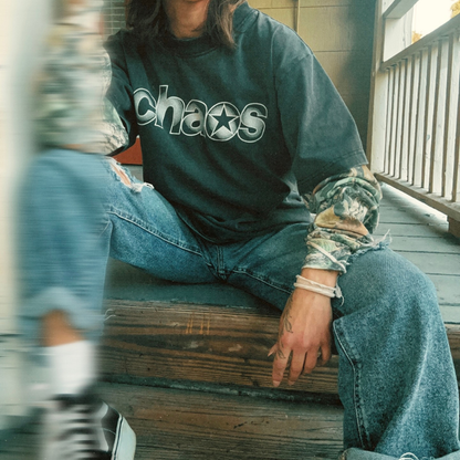 Person wearing a long sleeve with 'chaos' text sitting on steps.
