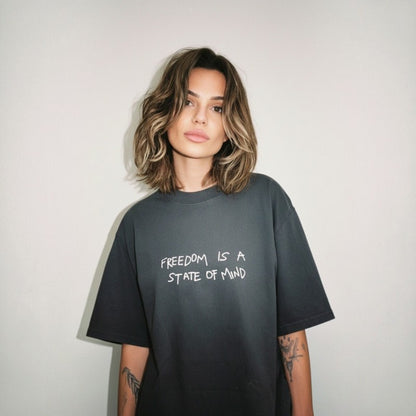 Person wearing a black t-shirt with 'Freedom is a State of Mind' text on a plain background