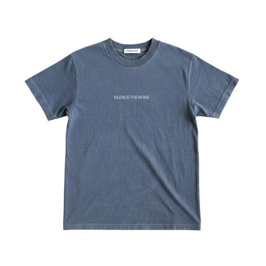 Front view of the Silence the Noise faded indigo t-shirt featuring a minimal white "SILENCE THE NOISE" text centered on the chest on a white background